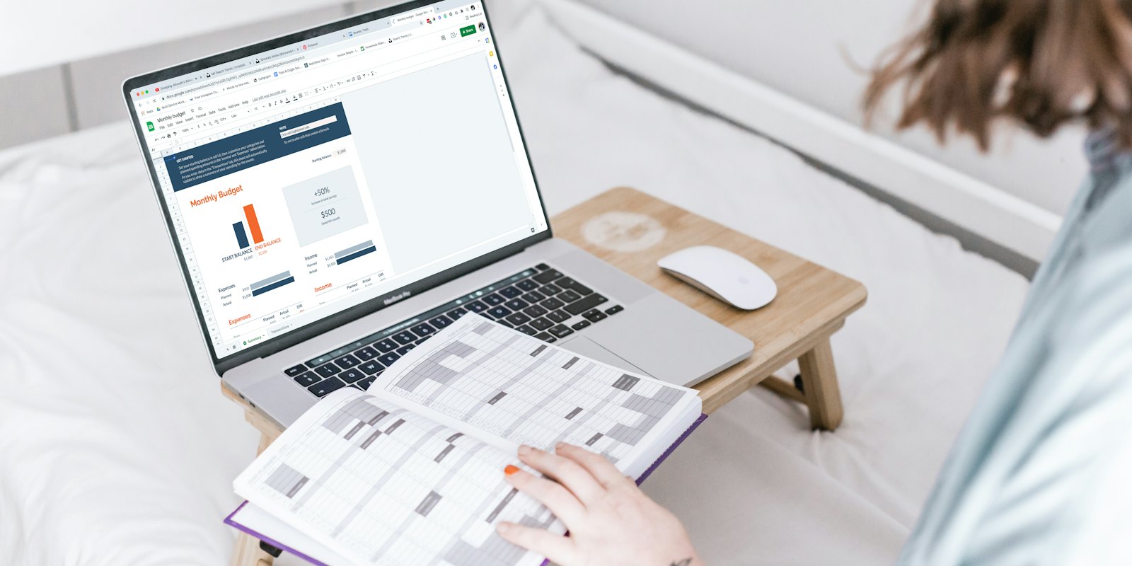 Someone working on a laptop with a planner open beside it