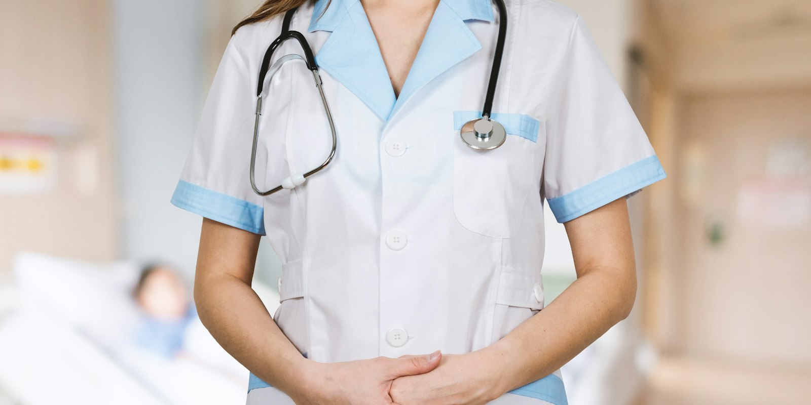 A healthcare worker in uniform standing in a corridor